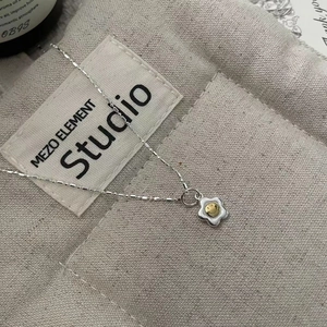 Detailed close-up of a S925 silver sunflower necklace with a gold smiley face pendant