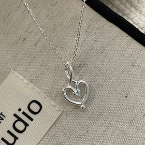 Minimalistische S925 Sterling Silber Herzanhänger Kette auf beigem Stoffhintergrund