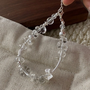 Detail of S925 silver beaded bracelet with clear white crystal and fan charm on wood