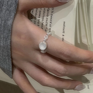 Elegante anello in argento sterling S925 con pietra bianca rotonda su sfondo di libro vintage