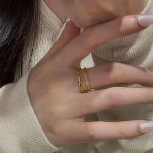 Close-up of minimalist gold double-layer silver ring with zircon on a soft background