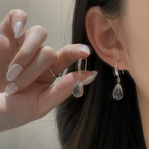 Macro shot of minimalist silver water drop earrings with transparent glass crystal pendants