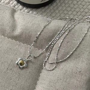 Macro shot of silver sunflower necklace with golden smiley face pendant and beaded chain