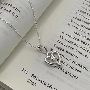 Nahaufnahme einer silbernen Doppelhalskette mit Herzanhänger auf Vintage-Buchseiten