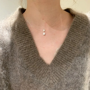 Nahaufnahme der minimalistischen zweischichtigen unsichtbaren Halskette mit Anhängern
