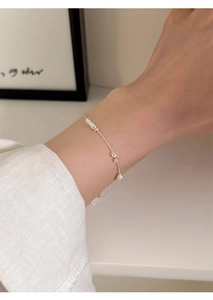 Minimalist S925 sterling silver beaded bracelet detail on wrist with soft lighting