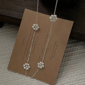 Détail du collier fleurs en mini perles d'argent 925 sur une carte en papier kraft