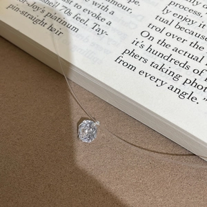 Close-up of invisible necklace featuring a sparkling rose-cut crystal on transparent line