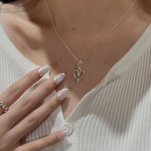 Detailaufnahme einer S925 Silber-Herzkette, kombiniert mit einer Strickjacke für Damen