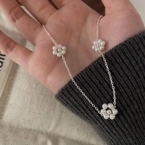 Vue détaillée d'un collier en argent 925 avec trois breloques fleurs en perles blanches