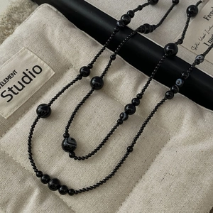 Minimalist S925 silver and black onyx beaded necklace displayed on a textured canvas bag