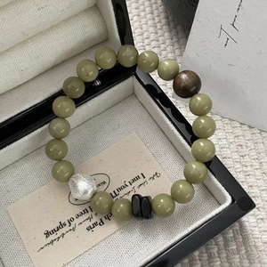 Detail of beaded S925 silver bracelet with green stones and wood bead in a gift box