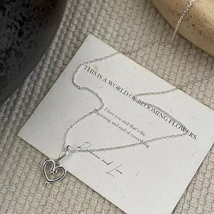 Nahaufnahme eines minimalistischen S925 Silber-Herzanhängers auf weichem Strickgewebe