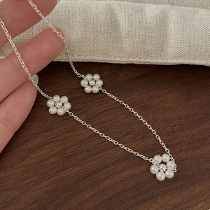 Détail du collier en argent 925 orné de trois mini fleurs de perles sur une chaîne fine