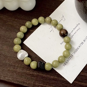 Detail view of S925 silver and green jade beaded bracelet on rustic wood background