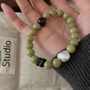 Detail of beaded bracelet featuring green sandalwood and silver irregular charm
