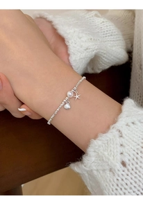 Detailed view of silver bead bracelet with pearl shell and starfish charms