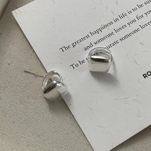 Close-up of minimalist square silver earrings on a card with elegant typography