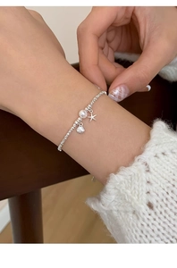 Detail of silver beaded bracelet with natural pearl, starfish and shell charms on wrist
