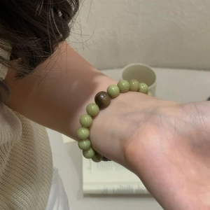 Detail of S925 sterling silver beaded bracelet with green stones and wood bead on wrist