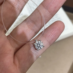 Nahaufnahme eines Anhängers mit rundem Brillantschliff-Diamant an klarer Angelschnur