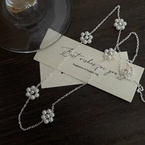 Gros plan détaillé du collier fleur en argent 925 avec mini perles sur bois