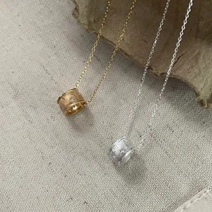Macro detail of brushed silver and gold star pendant necklaces on textured fabric