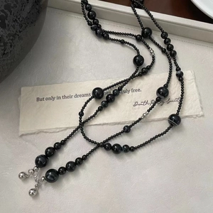 Macro detail of S925 silver beads and black agate necklace on a textured gray tray
