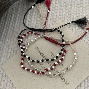 Détails de bracelets tressés à la main avec perles argentées et pompons