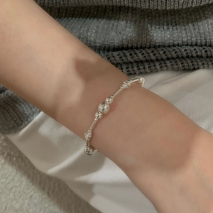 Bracelet minimaliste en argent sterling S925 avec perles lisses au poignet d'une femme