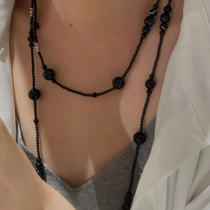 Elegant long S925 silver and black onyx beaded necklace layered over a white shirt