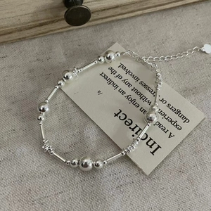 Gros plan sur un bracelet en argent sterling S925 avec billes polies et tubes lisses