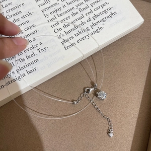 Nahaufnahme der minimalistischen unsichtbaren Angelschnurkette mit glitzerndem Anhänger