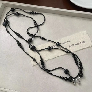Detail of multi-layered black agate bead necklace with silver bells on leather tray