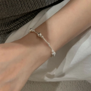Détail d'un bracelet en perles d'argent avec sphères métalliques sur le poignet