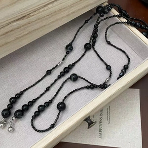 Close-up of black onyx beads with striped accents and silver bell on a S925 silver necklace