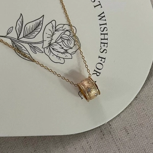 Close-up of brushed gold cylinder pendant with zircon stones on minimalist necklace