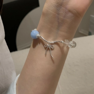 Close-up of S925 silver bracelet featuring aquamarine beads and a delicate bow pendant