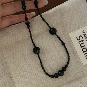 Detail of natural black agate beaded necklace with unique white veined textures