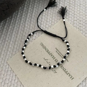 Détail du bracelet tissé noir ajustable avec perles géométriques argentées et gland