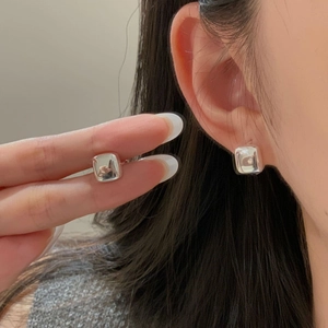 Detail view of a square S925 sterling silver earring with clear cubic zirconia on the ear