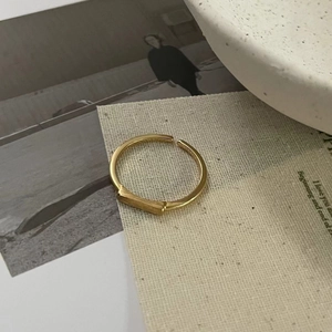 Artistic macro of a minimalist gold geometric square matte ring on textured paper