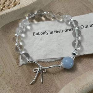 Detail shot of a beaded silver bracelet with blue crystal and a silver bow pendant