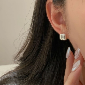 Close-up of minimalist square silver earrings on model featuring a polished mirror finish