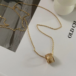 Detail of gold brushed cylinder pendant necklace with sparkling zircon star accents