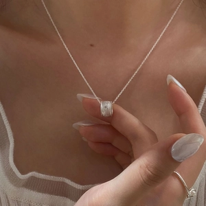 Macro detail of S925 silver cylinder pendant necklace and matching ring on model