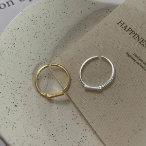 Detail of adjustable gold and silver geometric rings on a textured ceramic surface