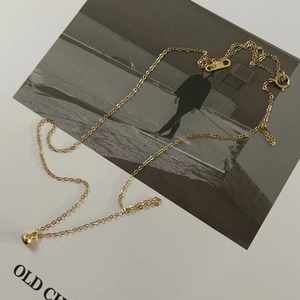 Macro detail of a minimalist gold bead pendant on a delicate silver cable chain necklace