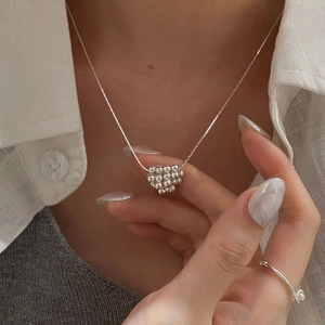 Détail macro du collier cœur en argent S925 et de la bague en perles sur le mannequin