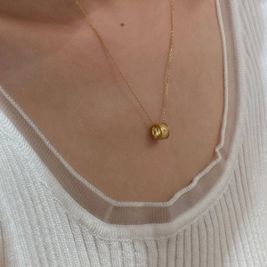 Close-up of a gold S925 sterling silver star-engraved cylinder pendant necklace on a model